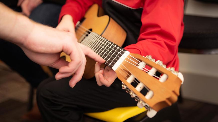 Music teacher teaching a child to play guitar.